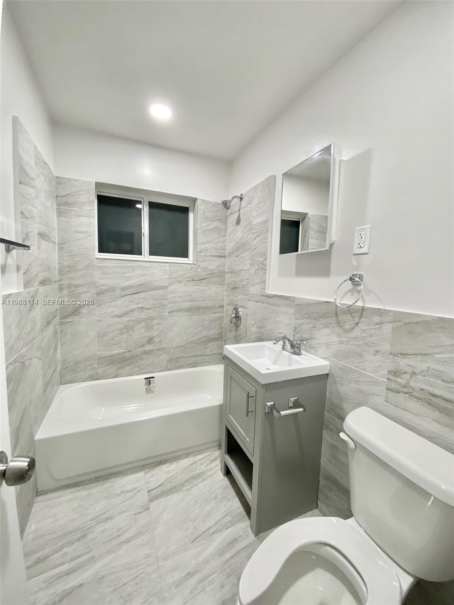 64 Northeast 78th Street, Unit 2 Miami, FL 33138 - Photo 2 of 11 a bathroom with a granite countertop sink a toilet and bathtub