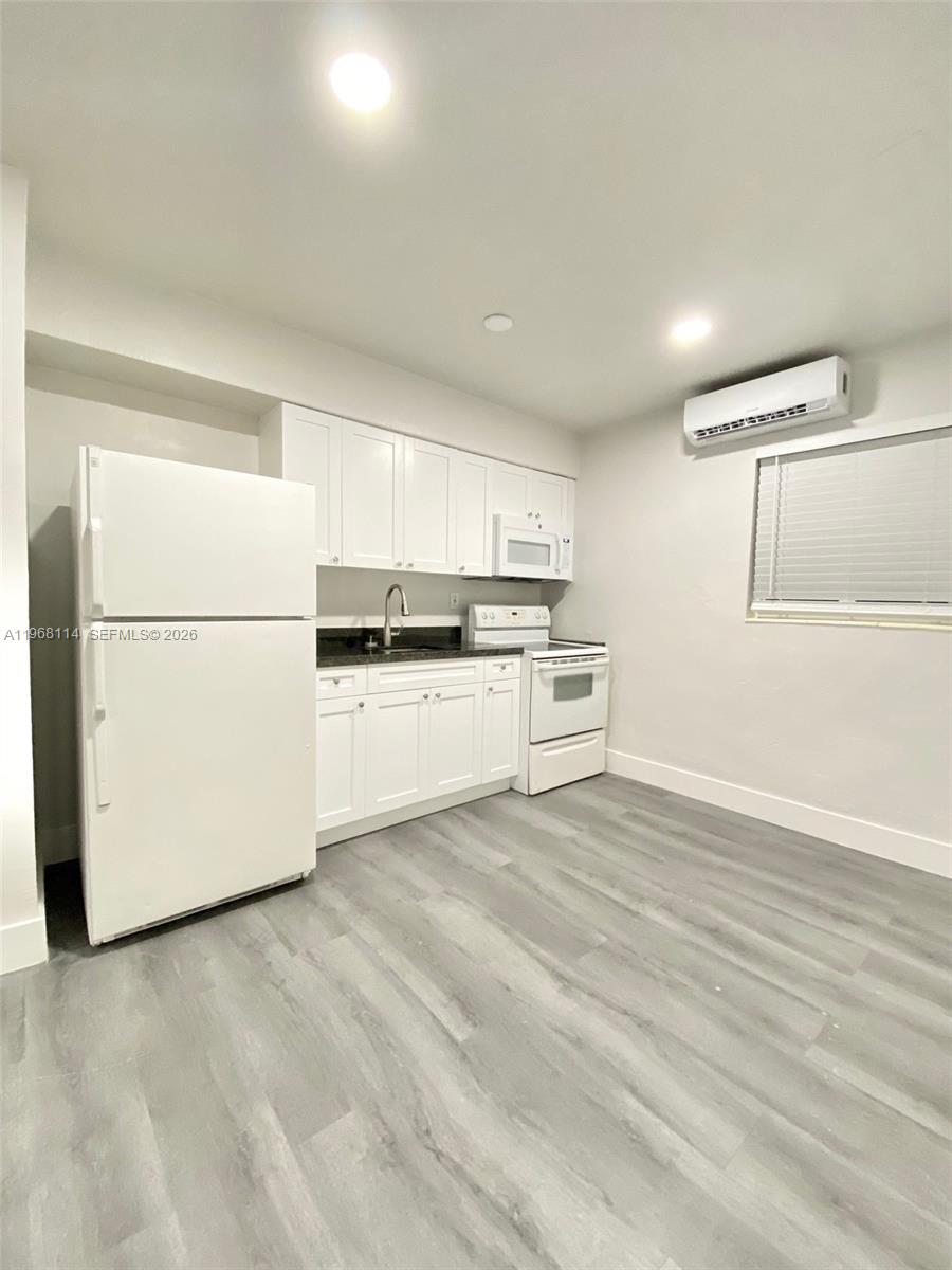 64 Northeast 78th Street, Unit 2 Miami, FL 33138 - Photo 5 of 11 a kitchen with a refrigerator a sink and white cabinets