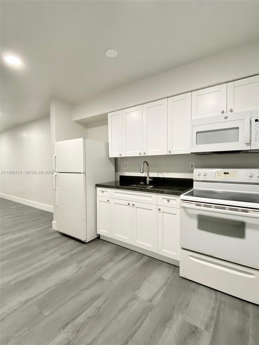 64 Northeast 78th Street, Unit 2 Miami, FL 33138 - Photo 6 of 11 a kitchen with granite countertop white cabinets and white appliances