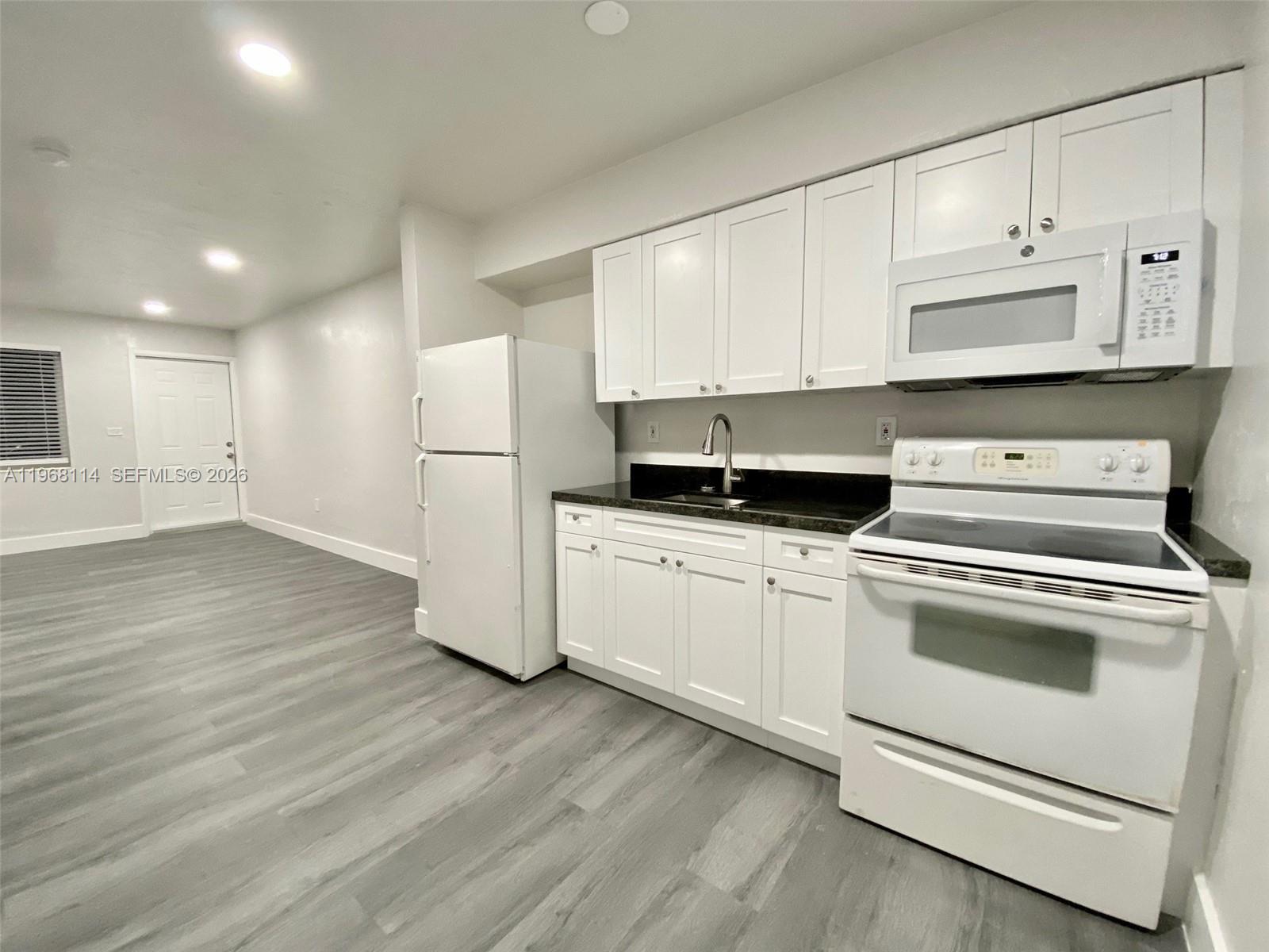 64 Northeast 78th Street, Unit 2 Miami, FL 33138 - Photo 7 of 11 a kitchen with a white cabinets and wooden floor