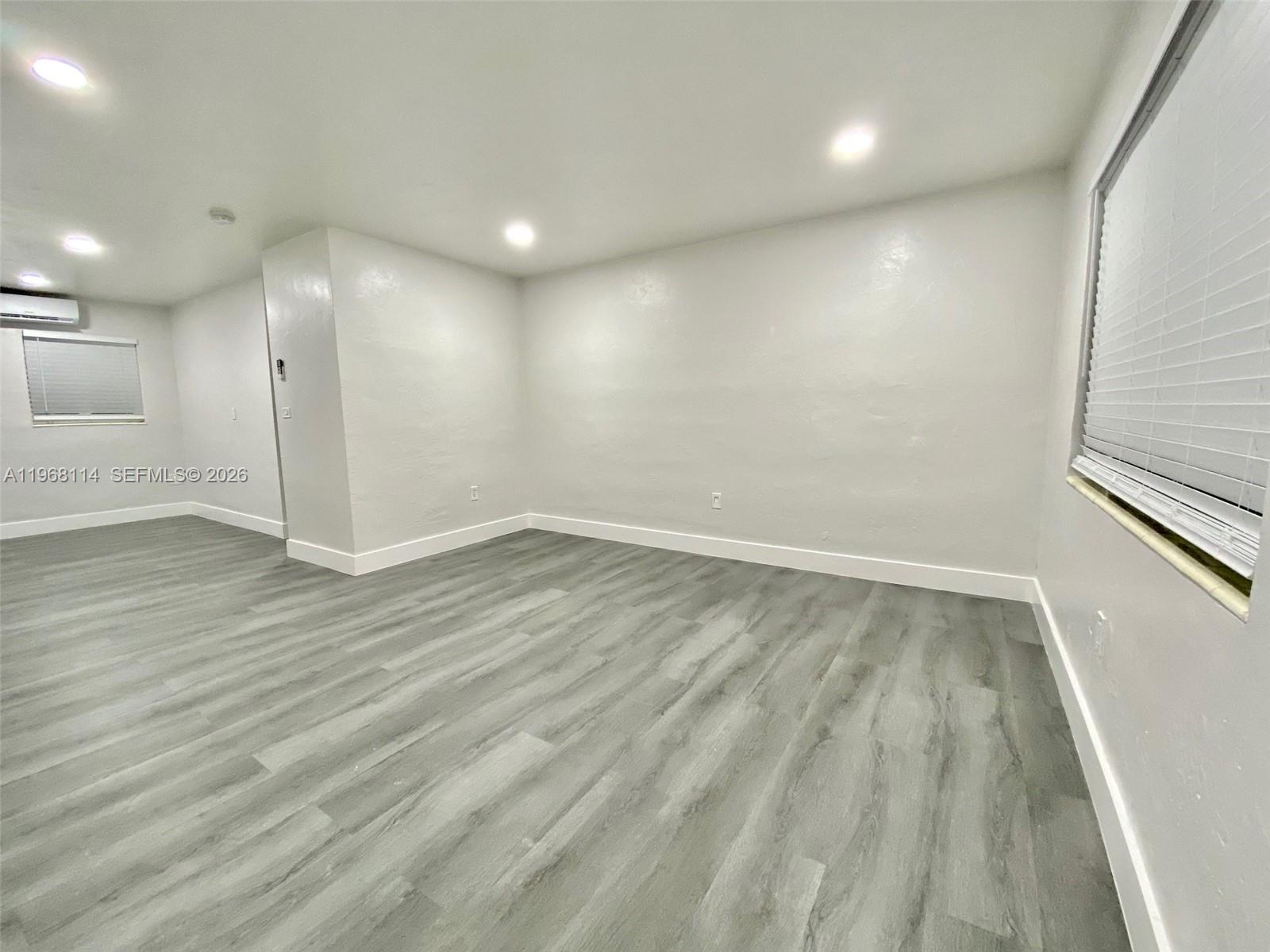 64 Northeast 78th Street, Unit 2 Miami, FL 33138 - Photo 9 of 11 an empty room with wooden floor and windows