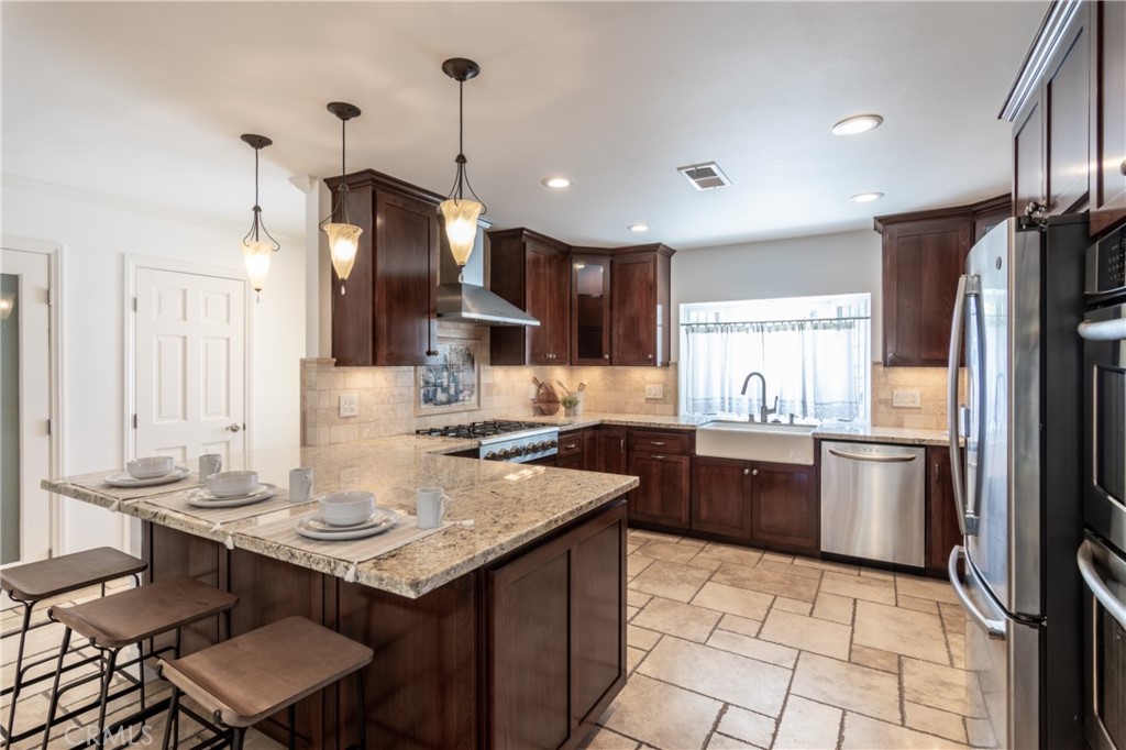 28009 Newbird Drive Saugus, CA 91350 - Photo 5 of 26 a kitchen with a sink a stove a refrigerator and chairs