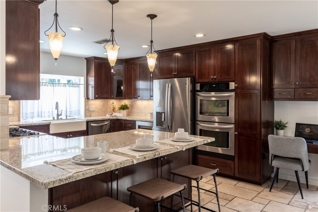 28009 Newbird Drive Saugus, CA 91350 - Photo 6 of 26 a kitchen with stainless steel appliances kitchen island granite countertop a dining table and chairs