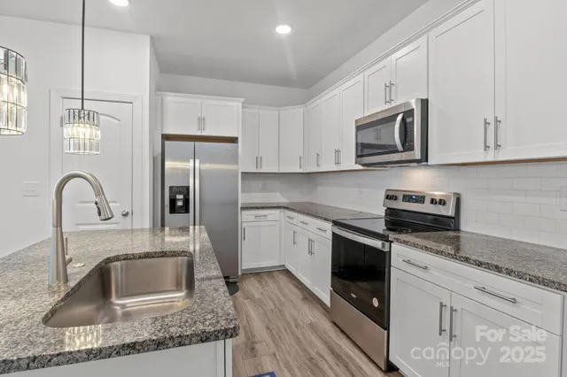 a kitchen with stainless steel appliances granite countertop a sink stove and refrigerator