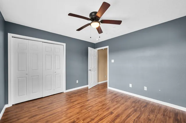 an empty room with wooden floor and ceiling fan