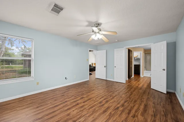 a view of an empty room with window and wooden floor