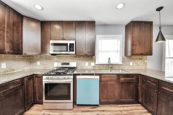 a kitchen with granite countertop wooden cabinets stainless steel appliances and a sink