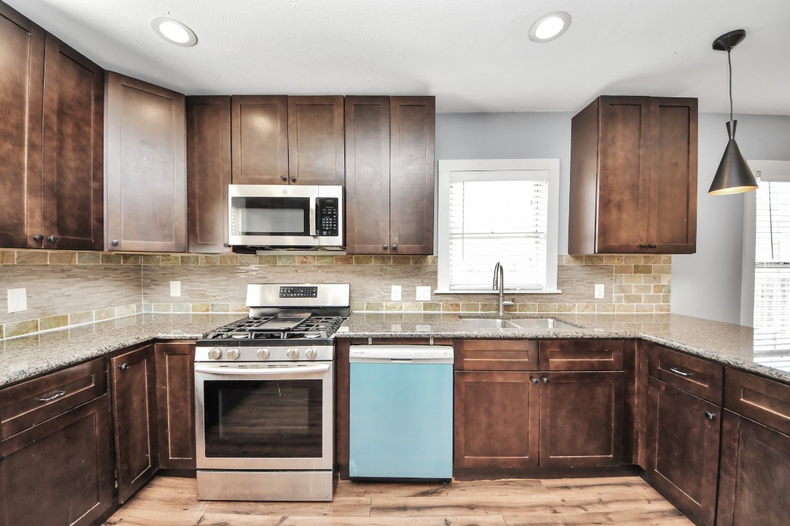 2820 Holman Street Houston, TX 77004 - Photo 16 of 38 a kitchen with granite countertop wooden cabinets stainless steel appliances and a sink