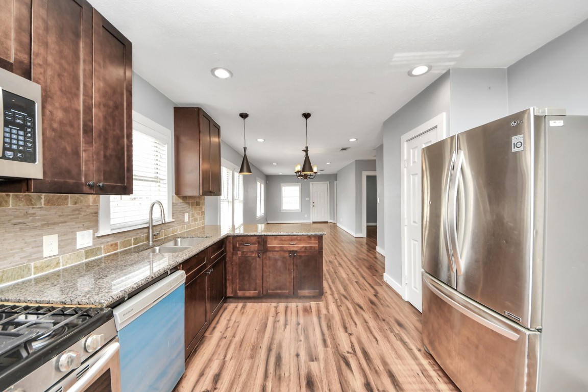 2820 Holman Street Houston, TX 77004 - Photo 18 of 38 a large kitchen with granite countertop a refrigerator a sink dishwasher a stove and white countertops with wooden floor