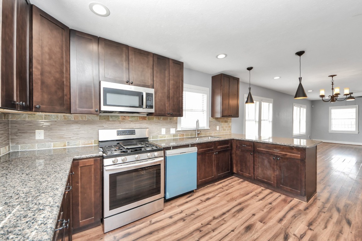 2820 Holman Street Houston, TX 77004 - Photo 19 of 38 a large kitchen with granite countertop stainless steel appliances wooden cabinets and a stove top oven