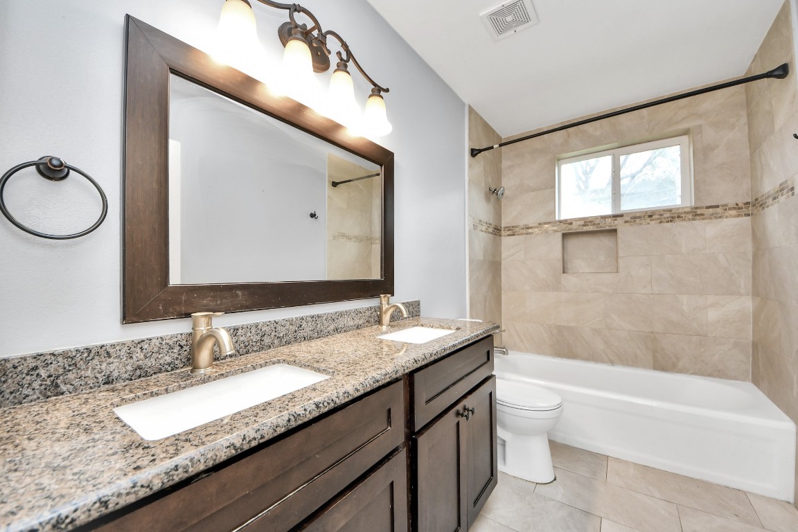 2820 Holman Street Houston, TX 77004 - Photo 24 of 38 a bathroom with a granite countertop sink mirror vanity bathtub and a toilet