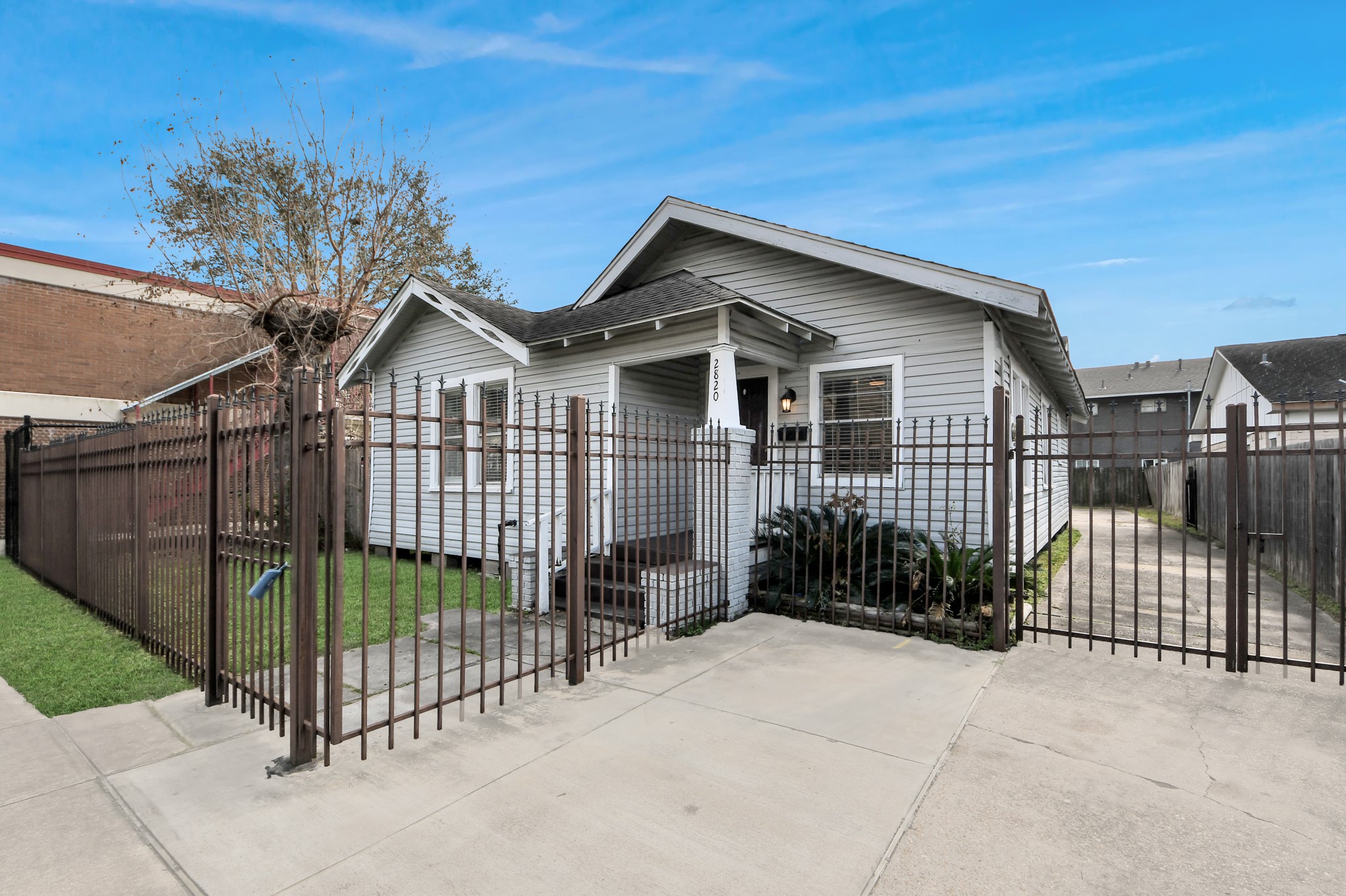 2820 Holman Street Houston, TX 77004 - Photo 3 of 38 Another view of the exterior featuring a classic contemporay home, a gated driveway, and a small lawn area for easy maintenance. Perfect for renters seeking a cozy, well-protected residence.