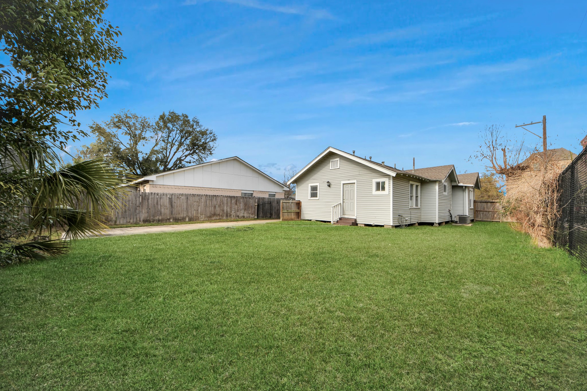 2820 Holman Street Houston, TX 77004 - Photo 32 of 38 This photo shows a cozy, single-story house with light siding, situated on a spacious, fenced-in grassy yard. Perfect for outdoor activities or future landscaping.