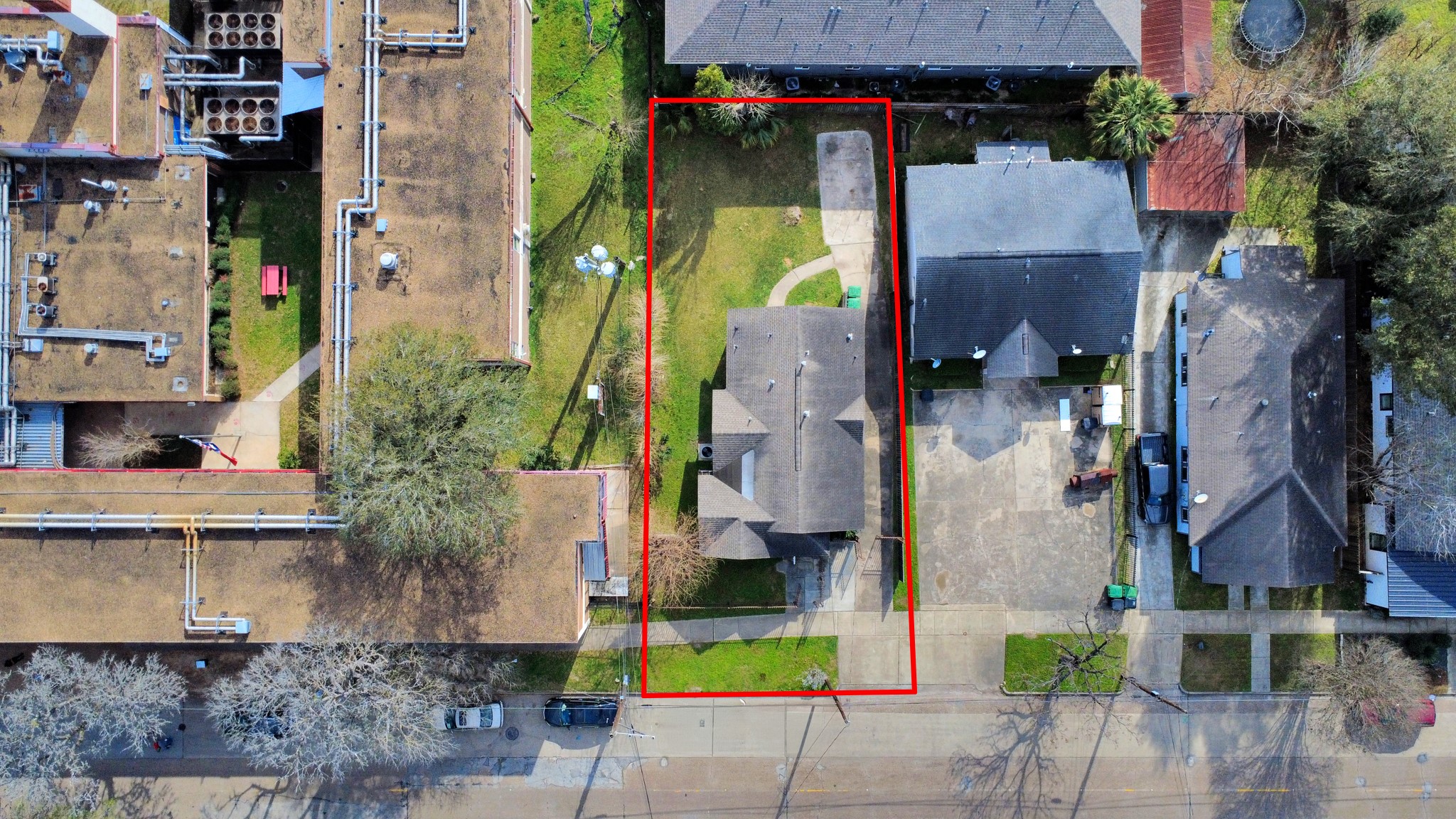 2820 Holman Street Houston, TX 77004 - Photo 35 of 38 This aerial photo shows a property outlined in red, featuring a single-family home with a driveway and front yard. It's situated in a residential neighborhood with adjacent houses and a nearby building.