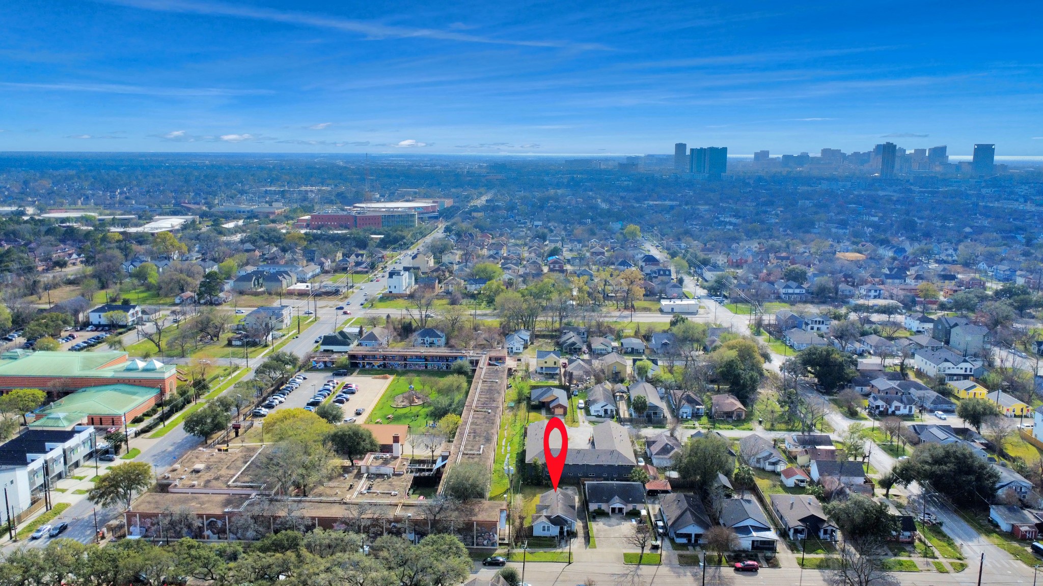 2820 Holman Street Houston, TX 77004 - Photo 36 of 38 This aerial photo showcases a suburban neighborhood with a mix of single-family homes, tree-lined streets, and nearby amenities. The red marker highlights a specific property, offering a convenient location with city views in the distance.