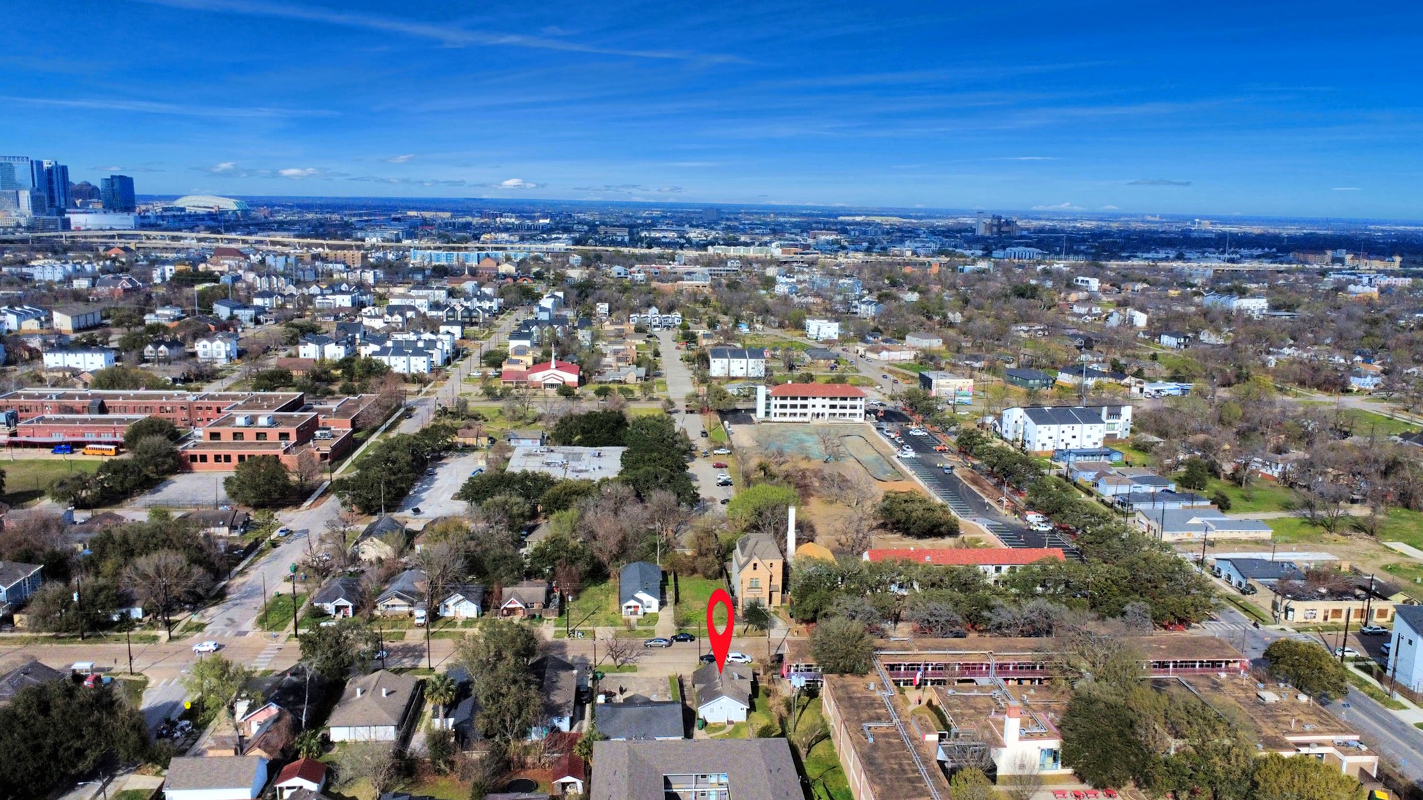 2820 Holman Street Houston, TX 77004 - Photo 37 of 38 This aerial photo showcases a residential neighborhood with a mix of houses and greenery. The area is close to a city center, visible in the background, offering a balance of suburban and urban living. A specific property is marked for easy identification.