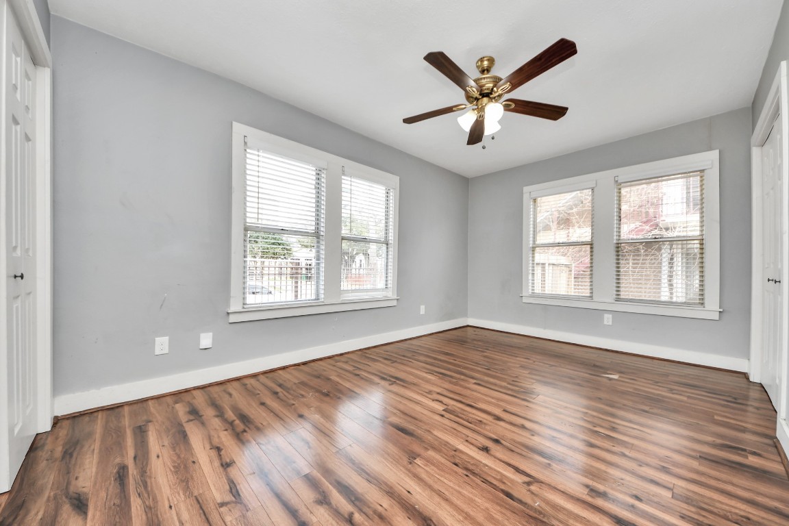 2820 Holman Street Houston, TX 77004 - Photo 5 of 38 an empty room with wooden floor a ceiling fan and windows