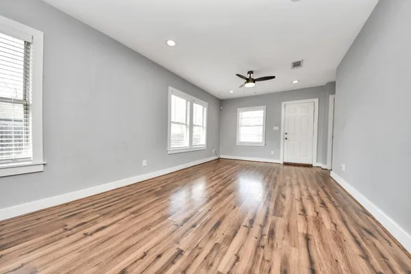 an empty room with wooden floor and windows