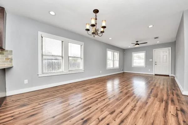 a view of an empty room with a window and wooden floor