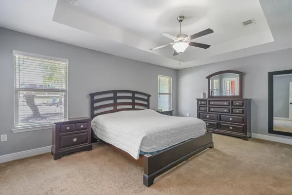 a bedroom with a bed a dresser and a chandelier