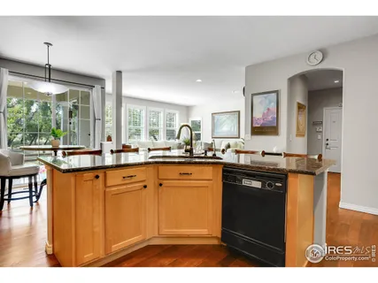 a kitchen with stainless steel appliances kitchen island granite countertop a sink and wooden floor
