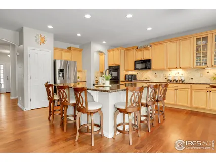 a kitchen with stainless steel appliances kitchen island granite countertop a table chairs and a refrigerator