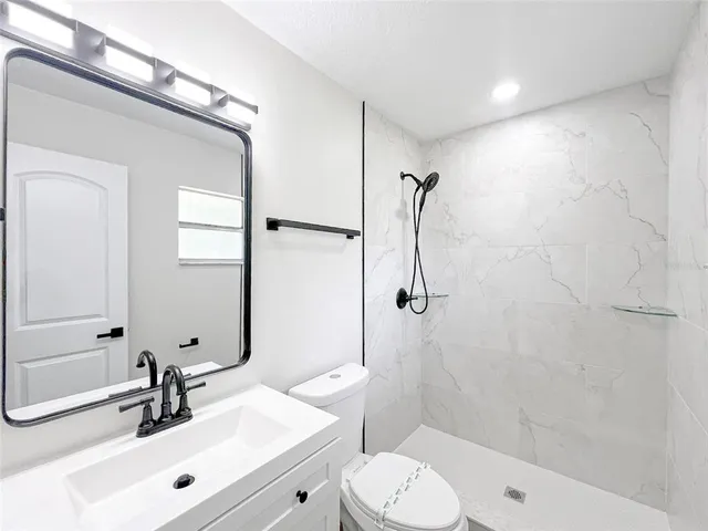 a bathroom with a sink mirror toilet and shower