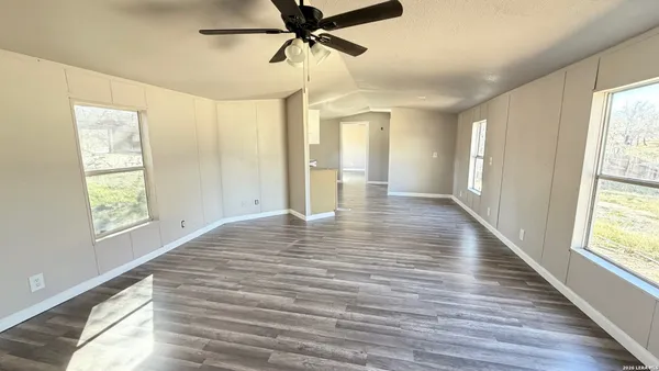a view of empty room with wooden floor and fan