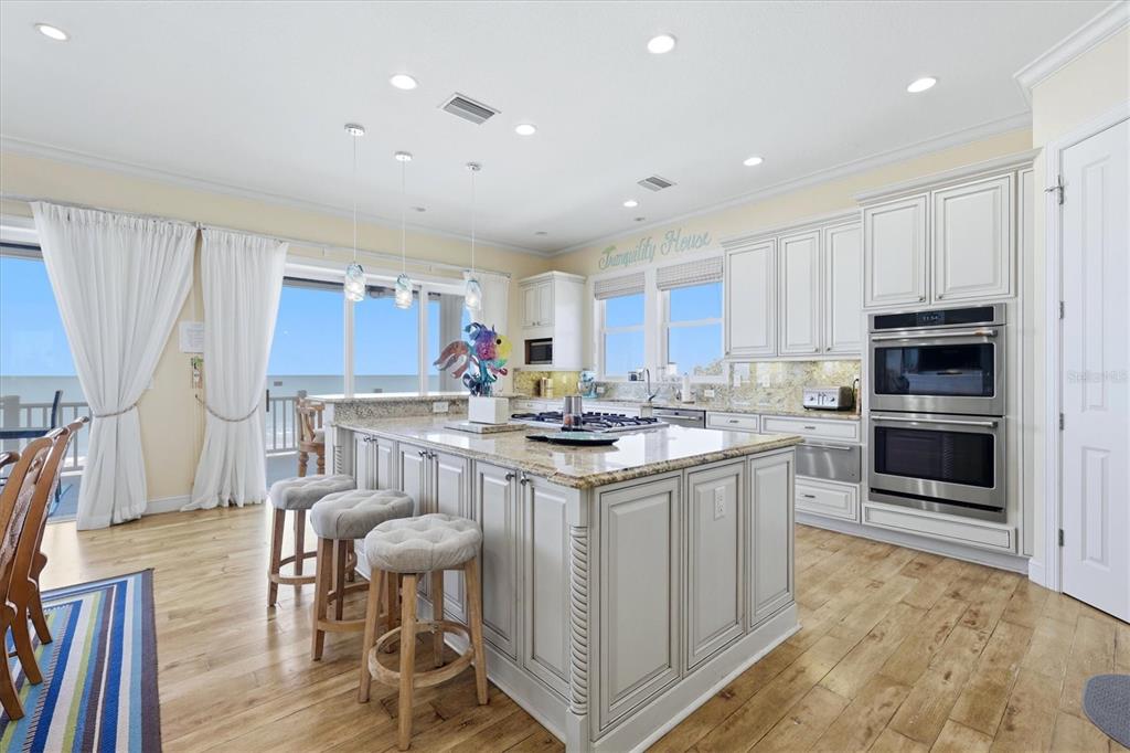 131 South Gulf Boulevard Boca Grande, FL 33921 - Photo 19 of 59 a kitchen with stainless steel appliances granite countertop a stove top oven a refrigerator a dining table and chairs with wooden floor