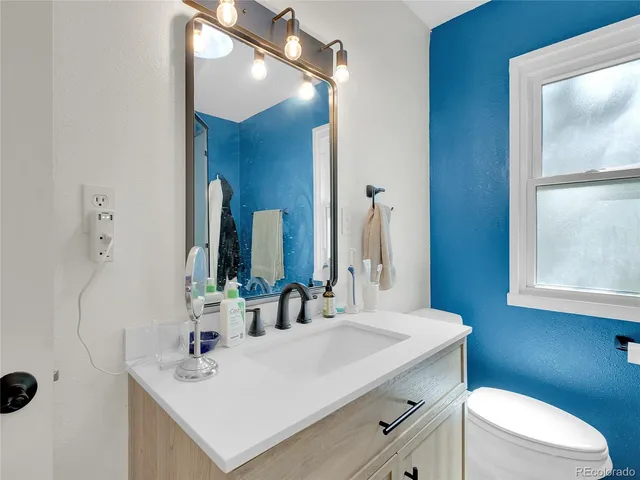 a bathroom with a sink vanity toilet and a mirror