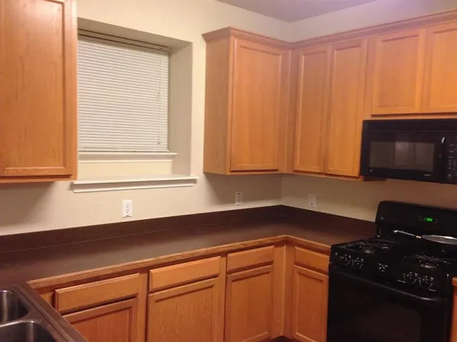 a kitchen with granite countertop white cabinets and black appliances