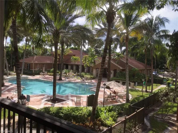 a palm tree sitting in front of a house with a fountain