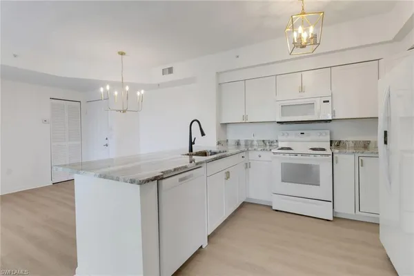 a kitchen with granite countertop white cabinets and white appliances