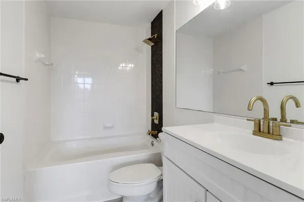 a bathroom with a granite countertop sink a toilet and bathtub