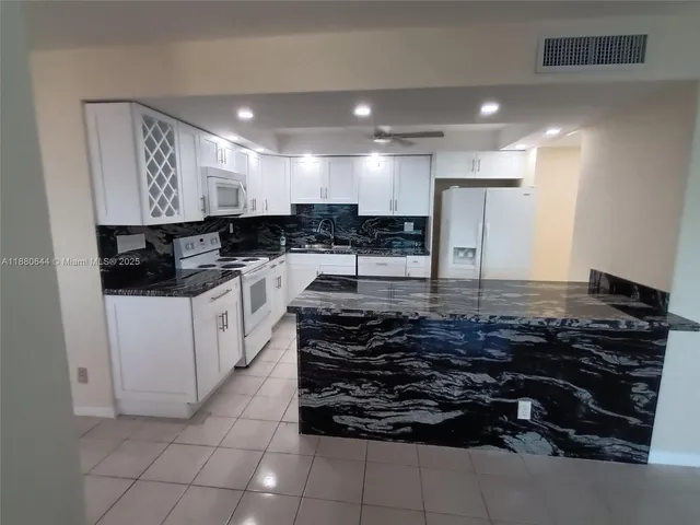 a kitchen with kitchen island granite countertop a stove and a sink