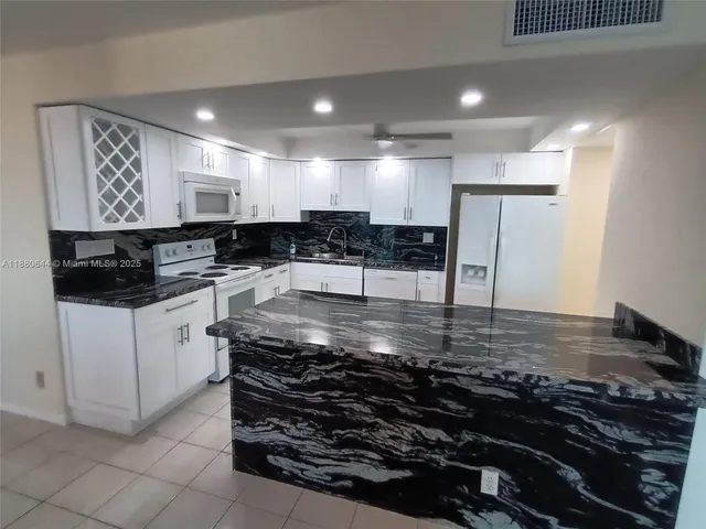 a kitchen with kitchen island granite countertop a sink and a stove