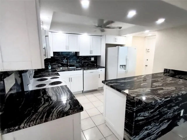 a kitchen with kitchen island granite countertop a stove and a refrigerator