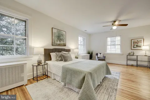 a bedroom with a large bed a chandelier and windows
