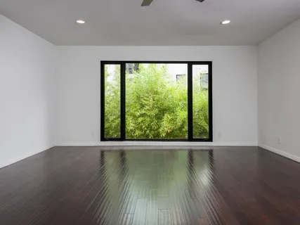 a view of an empty room with wooden floor and a window