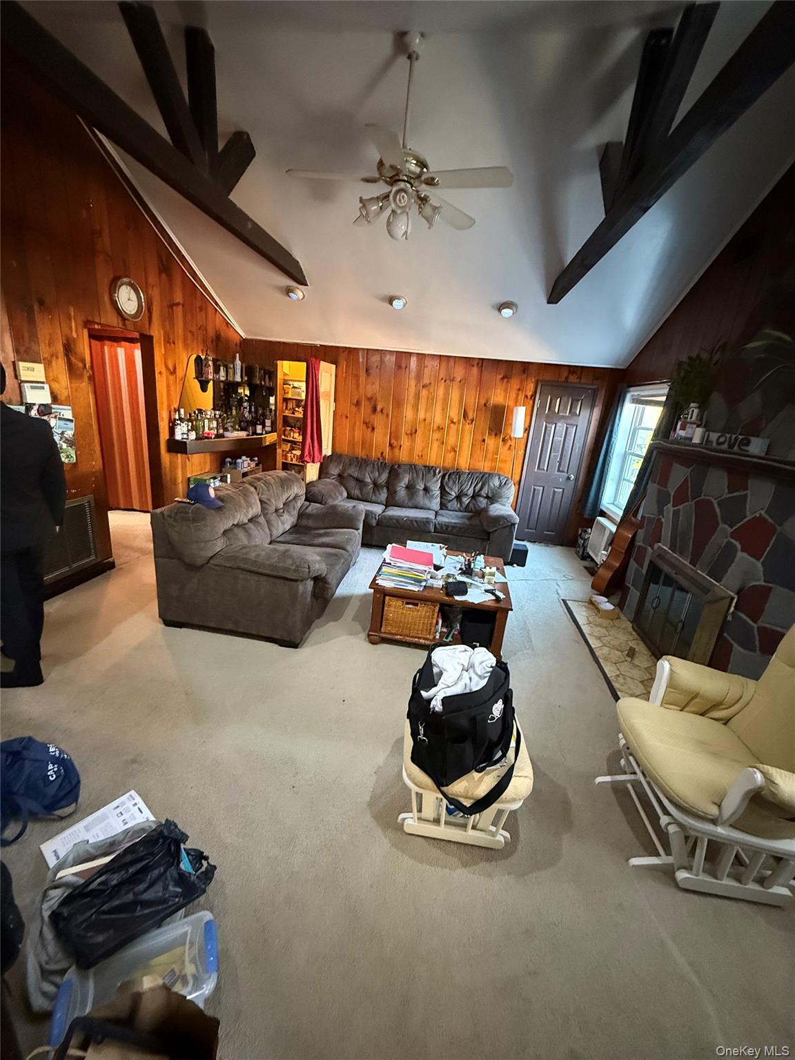 Undisclosed Address West Babylon, NY 11704 - Photo 2 of 8 Carpeted living area with wooden walls, beamed ceiling, and high vaulted ceiling