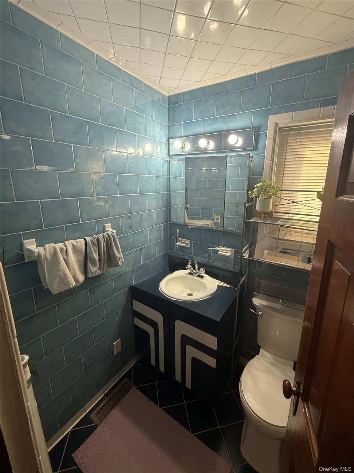 Undisclosed Address West Babylon, NY 11704 - Photo 5 of 8 Half bath with tile walls, dark tile patterned floors, and vanity