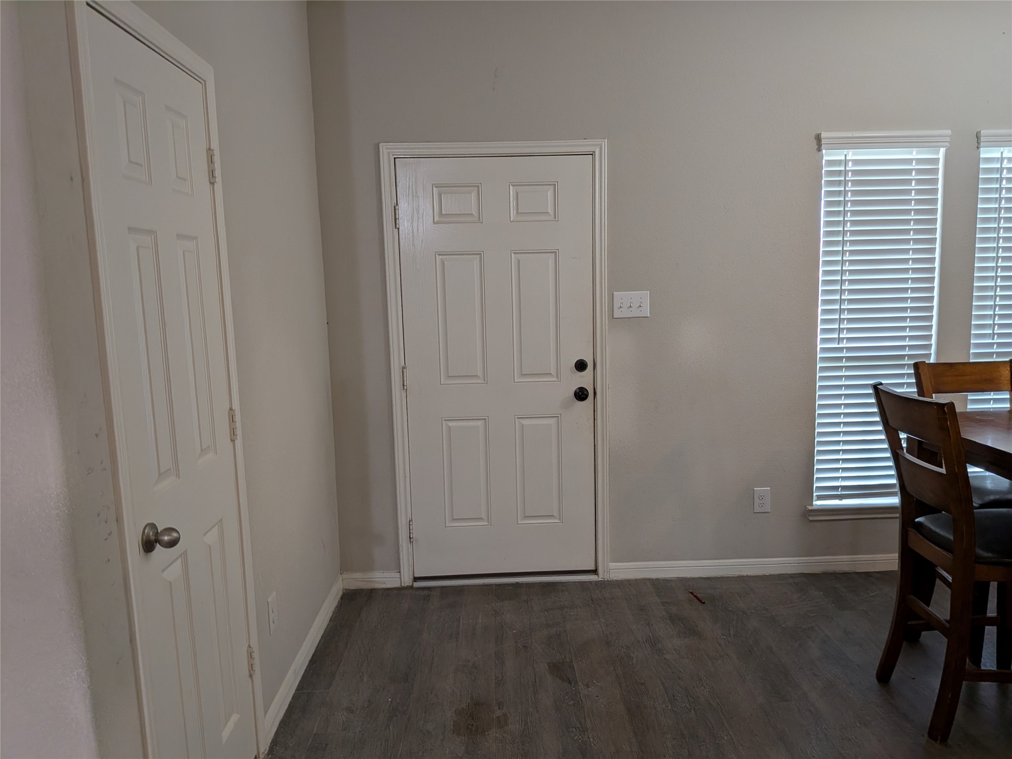 15730 Joe Dimaggio Street Splendora, TX 77372 - Photo 4 of 20 This photo shows an entryway with a white door, adjacent to a dining area with large windows and blinds. The space features light-colored walls and wood flooring, creating a welcoming atmosphere.