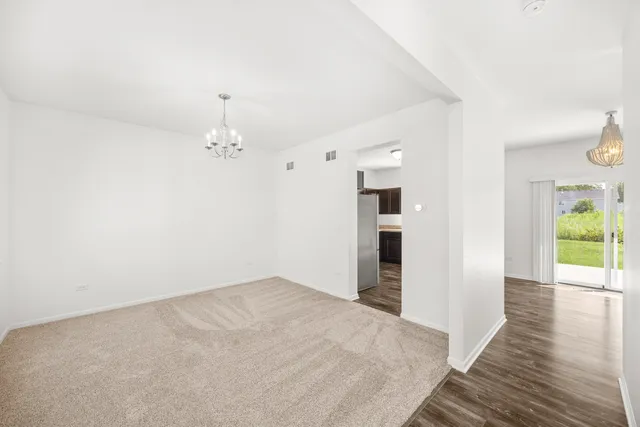 a view of a hallway with wooden floor and chandelier