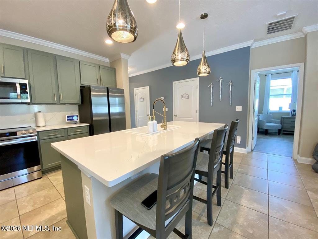 115 Sierras Loop St. Augustine, FL 32086 - Photo 18 of 65 a kitchen with stainless steel appliances kitchen island granite countertop a table chairs sink and cabinets