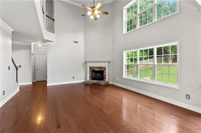 an empty room with wooden floor a ceiling fan and windows