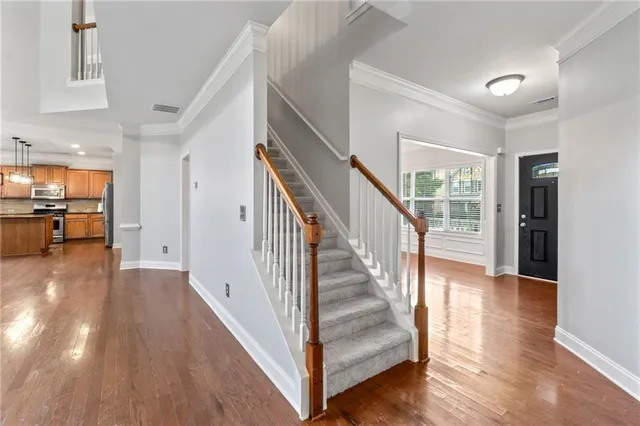 a kitchen with stainless steel appliances granite countertop wooden floors wooden cabinets a window and a sink