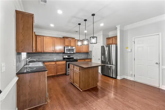 a kitchen with stainless steel appliances granite countertop a sink a stove a refrigerator cabinets and wooden floor