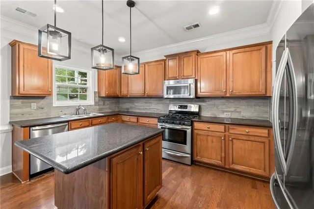 a kitchen with stainless steel appliances granite countertop a sink a stove a microwave cabinets and a window