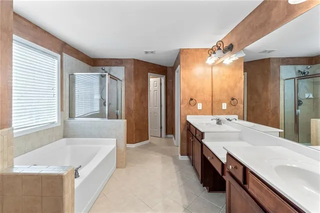 a spacious bathroom with a granite countertop sink a large mirror and a bathtub