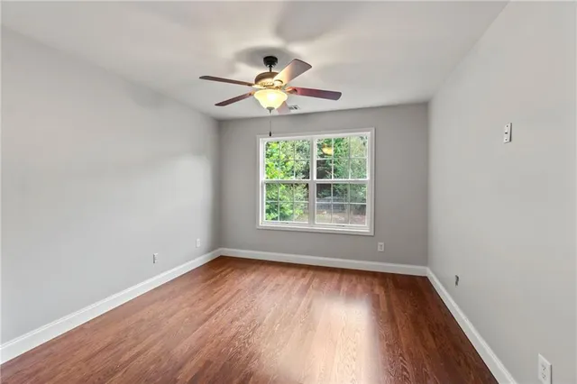an empty room with wooden floor a ceiling fan and closet
